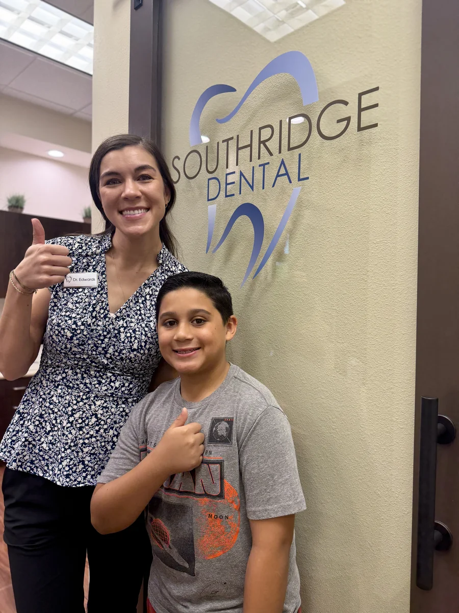 Dr Edwards Henderson Pediatric Dentist With Young Patient By Office Logo